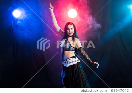 Young woman belly dancer in exotic dress with gold, dancing tribal fusion dance in studio. Young woman belly dancer in exotic dress with gold, dancing tribal fusion dance in studio. 65647042