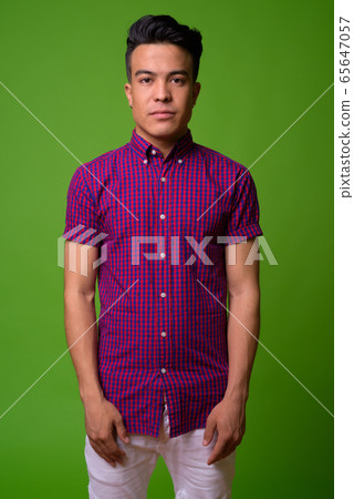 Young multi-ethnic man wearing purple shirt against green background Young multi-ethnic man wearing purple shirt against green background 65647057