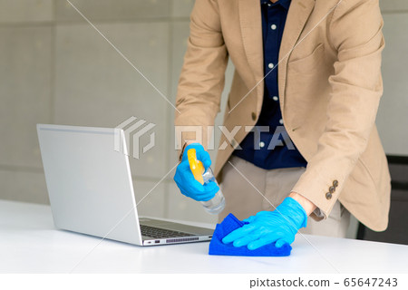 Business woman wearing mask and using personal sanitizer to cleaning his office 65647243