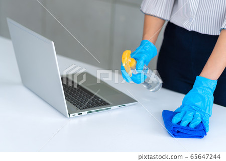 Business woman wearing mask and using personal sanitizer to cleaning her table in office 65647244