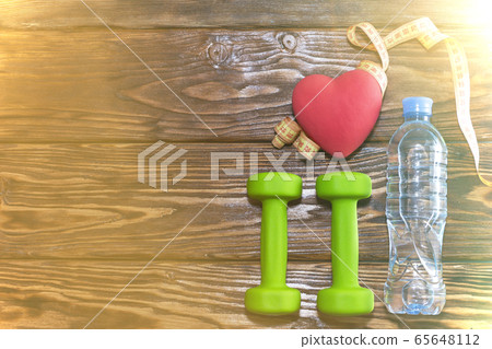 Dumbbells and a red heart on a wooden background. The concept of a healthy lifestyle. 65648112