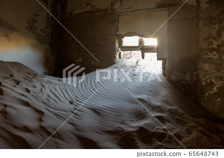 Abandoned and forgotten building and room left by people and being taken over by encroaching sandstorm, Kolmanskop ghost town, Namib Desert 65648743