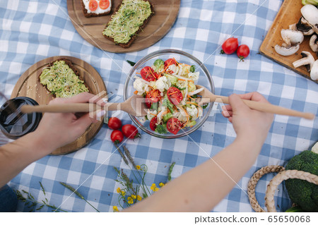 First person view of Woman mix vegan salad on picnic outside. Vegan food concept First person view of Woman mix vegan salad on picnic outside. Vegan food concept 65650068