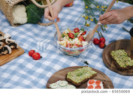 Woman mix vegan salad on picnic outside. Vegan food concept Woman mix vegan salad on picnic outside. Vegan food concept 65650069