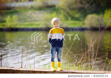 Preschooler child wearing yellow rain boots  walking near river 65650131