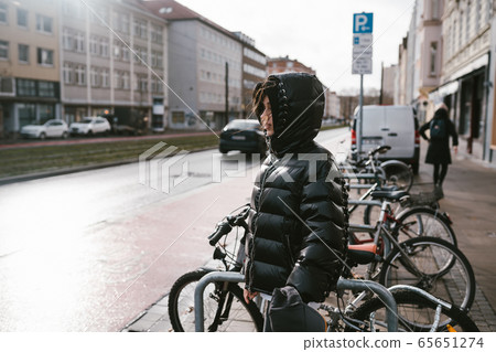 Young woman picks up her bike from the parking lot 65651274