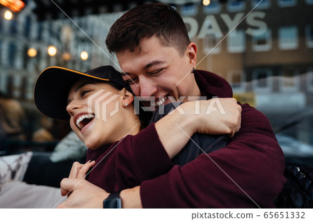 Guy and a girl are hugging at a table in a outdoor cafe. Guy and a girl are hugging at a table in a outdoor cafe. 65651332