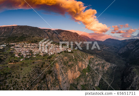 Aerial view of Delphi, Greece, the Gulf of Corinth, orange color of clouds, mountainside with layered hills beyond with rooftops in foreground 65651711