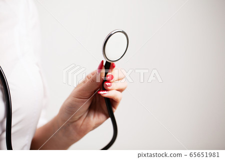 Female doctor in a white coat holding a stethoscope Female doctor in a white coat holding a stethoscope 65651981