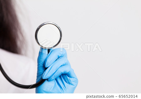 Female doctor in a white coat holding a stethoscope Female doctor in a white coat holding a stethoscope 65652014