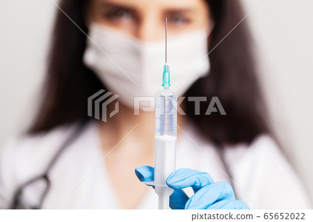 Female doctor in gloves holds a syringe with vaccine Female doctor in gloves holds a syringe with vaccine 65652022