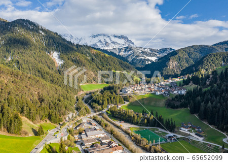 Aerial view of improbable green meadows of Italian Alps, Comano Terme, huge clouds over a valley, roof tops of houses, Dolomites on background, sunshines through clouds Aerial view of improbable green meadows of Italian Alps, Comano Terme, huge clouds over a valley, roof tops of houses, Dolomites on background, sunshines through clouds 65652099