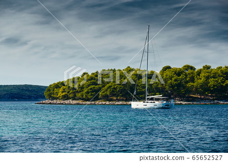 Beautiful sea landscape with lonely boat on the horizon, island is on background, bright colors Beautiful sea landscape with lonely boat on the horizon, island is on background, bright colors 65652527