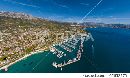 Croatia, marina Kastela, Drone view point on moored in an equal row sailboats, participant of a sailing regatta, piers, a lot of boats, mountains is on background, piers 65652573