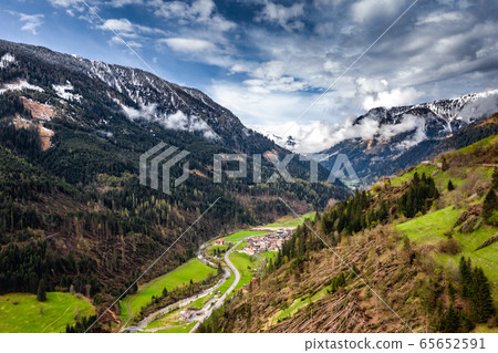 Aerial view of valley with green slopes of the mountains of Italy cloudy weather, Trentino, The trees tumbled down by a wind, huge clouds over a valley, green meadows, Dolomites on background 65652591