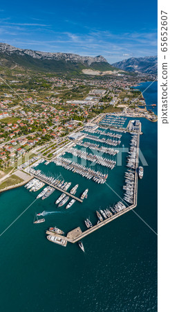 Croatia, marina Kastela, Drone view point on moored in an equal row sailboats, participant of a sailing regatta, piers, a lot of boats, mountains is on background, piers 65652607