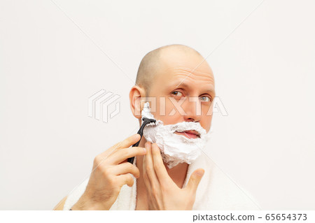 Man in the bathroom shaves his beard with a razor 65654373