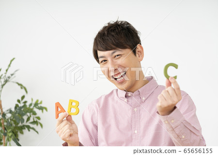 Man holding alphabet blocks and looking at camera looking at Man holding alphabet blocks and looking at camera looking at 65656155
