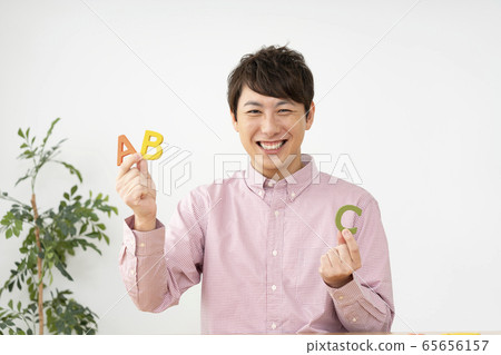 Man holding alphabet blocks and looking at camera looking at 65656157