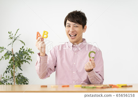 男子手持字母塊，看著相機看著 65656158