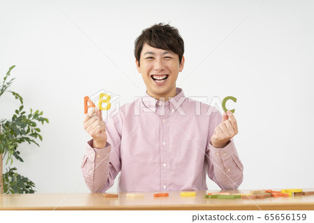 Man holding alphabet blocks and looking at camera looking at 65656159