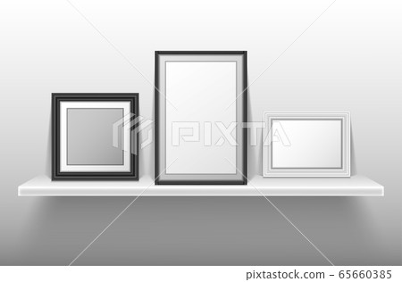 Empty photo frames standing on white shelf 65660385