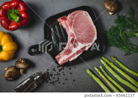 Top view of grilled pork steak surrounded by organic vegetable ingredients. 65661137