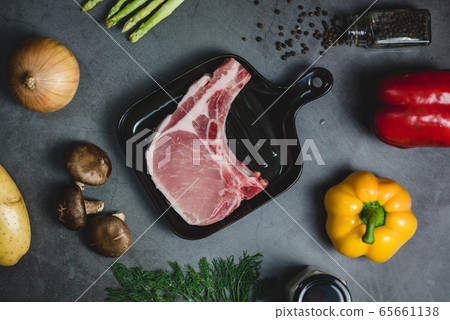Top view of grilled pork steak surrounded by organic vegetable ingredients. 65661138