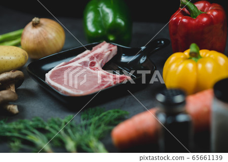 Side view of raw pork for prepare steak surrounded by organic vegetable ingredients. 65661139