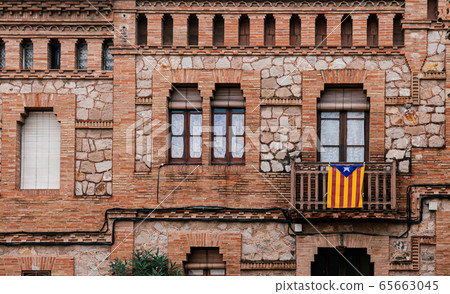 Red brick vintage building with Catalan flag in La Colonia Guell 65663045