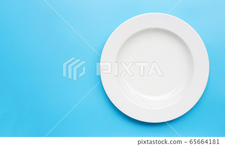 Empty white ceramic plate on blue background. Empty white ceramic plate on blue background. 65664181