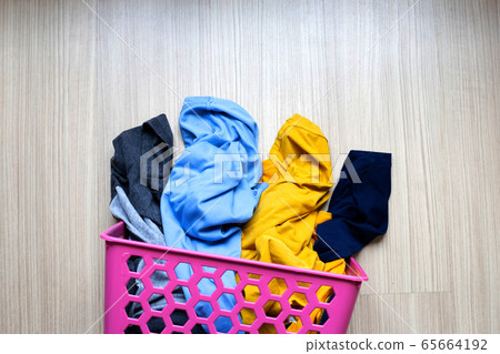 Clothes in pink plastic laundry basket. 65664192