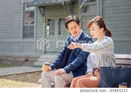 Business woman and businessman looking at wrist watch Business woman and businessman looking at wrist watch 65665235