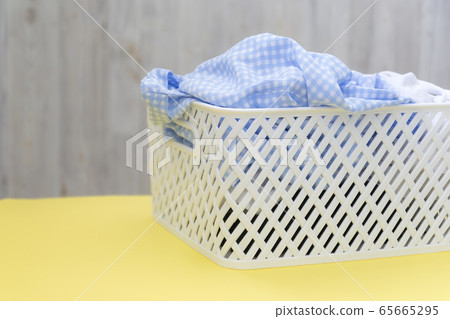 Blank blue white shirts in a white plastic basket on a yellow table on a gray background. Laundry, home cleaning, cleanliness and freshness Blank blue white shirts in a white plastic basket on a yellow table on a gray background. Laundry, home cleaning, cleanliness and freshness 65665295