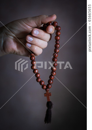womans hand with wooden rosary or prayer beads 65665655