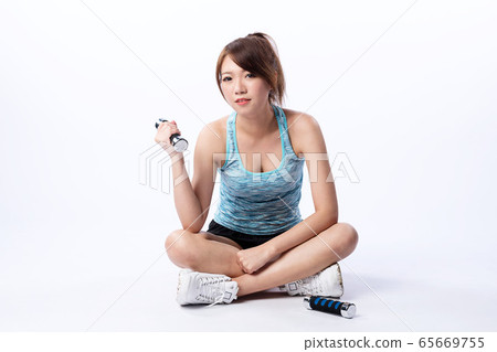 Cute Asian girl holding dumbbell while sitting on the floor Cute Asian girl holding dumbbell while sitting on the floor 65669755