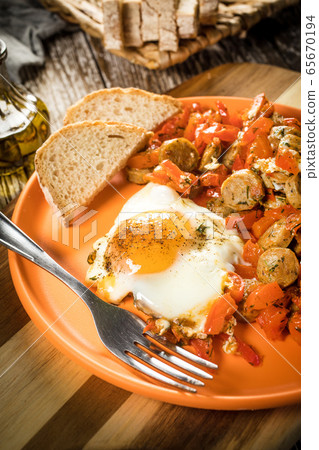 Fried vegetables with sausage and fried egg. 65670194