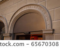 Building with a showcase. Empty plate in the form of an arch on an old house. Empty space for a number, text or store name on glass. Side view from below. Black metal minimal design for advertising. 65670308