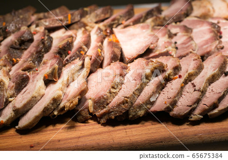 Sliced baked meat on a wooden board.  65675384