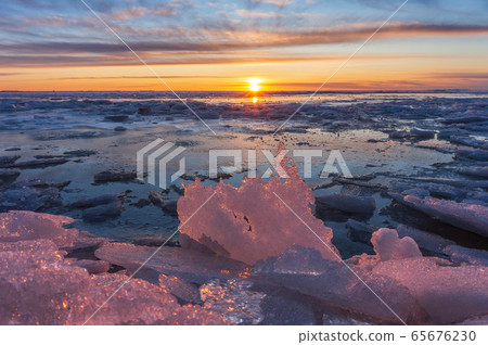 winter or spring sunset against the backdrop of a semi-frozen bay with pieces of ice and pink ice floes in the sun winter or spring sunset against the backdrop of a semi-frozen bay with pieces of ice and pink ice floes in the sun 65676230