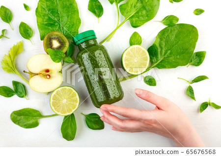 A woman's hand holds at her fingertips a bottle of green detox 65676568