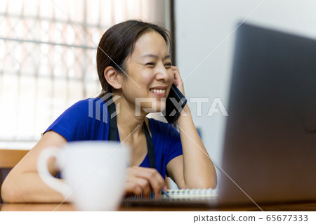 Happy woman talking on cell phone with open laptop on table work at home concept. 65677333
