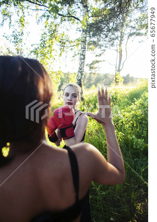 two diverse nations girls fighting boxing outside in green park, sport summer people concept two diverse nations girls fighting boxing outside in green park, sport summer people concept 65677949