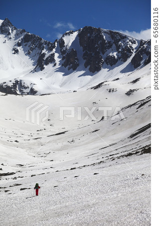 Hiker in high snowy mountains at nice spring day Hiker in high snowy mountains at nice spring day 65680116