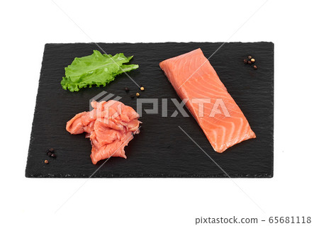 Sliced salmon fillet on the black shale board, with lemon and salad. On white background 65681118