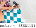 Contract worker using hammer and gouge to chisel or carve the tile from the wall for fixing wall. 65681131