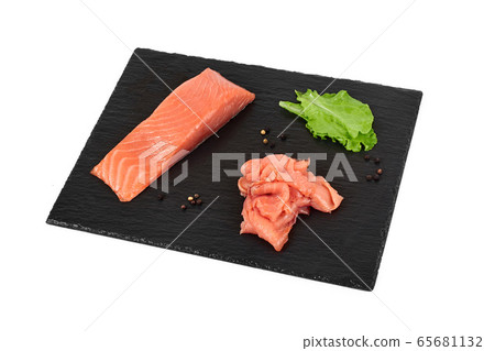Sliced salmon fillet on the black shale board, with lemon and salad. On white background 65681132