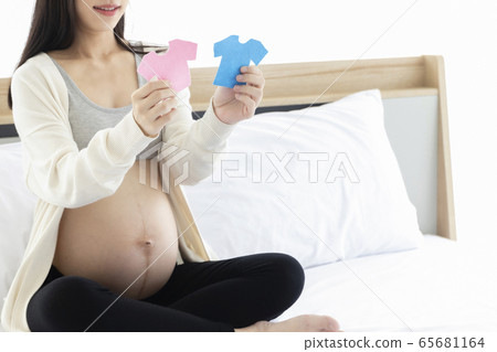 Pregnant Asian woman smiling and happy to be mom and imagine her child will be boy or girl. Pregnant Asian woman smiling and happy to be mom and imagine her child will be boy or girl. 65681164
