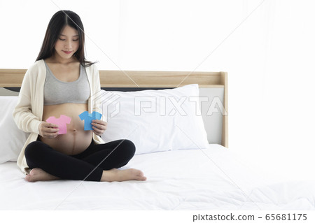 Pregnant Asian woman smiling and happy to be mom and imagine her child will be boy or girl. Pregnant Asian woman smiling and happy to be mom and imagine her child will be boy or girl. 65681175