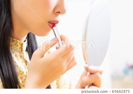 Woman applying lipstick and applying makeup Woman applying lipstick and applying makeup 65682875